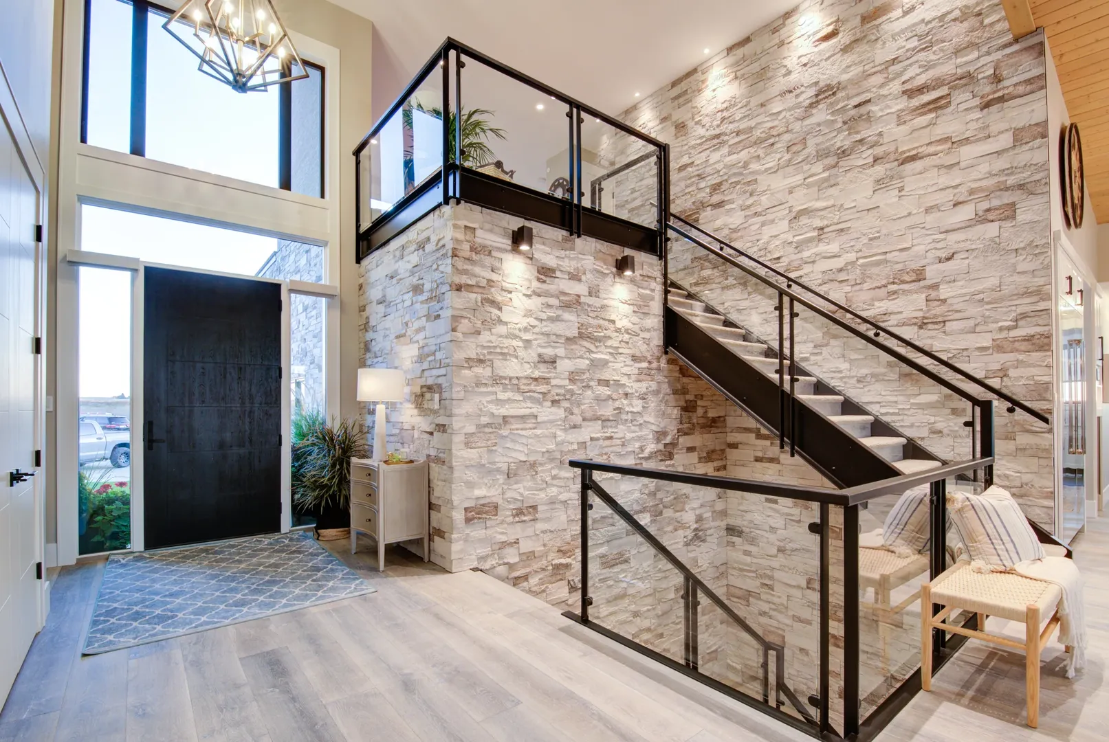 Custom Kenco staircase with natural stone walls, glass balustrades and precise black metalwork
